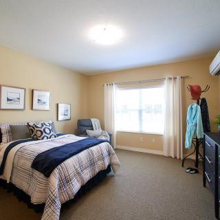 A cozy bedroom with a neatly made bed, soft lighting, and tasteful decor.
