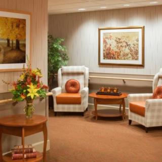 A cozy lobby with comfortable armchairs, decorative paintings, and a floral arrangement on a side table.