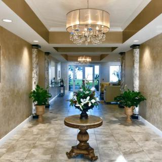 A luxurious lobby featuring a chandelier, decorative table, and greenery.