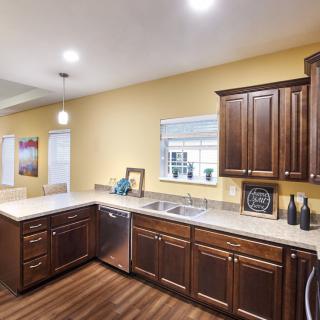 A modern kitchen with wooden cabinets, a sleek countertop, and ample lighting.