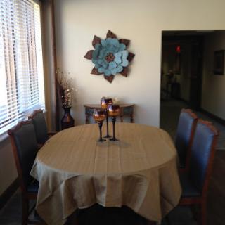 A cozy dining area featuring a round table set with candle holders, surrounded by wooden chairs and adorned with decorative wall art.