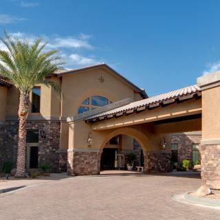 A residential building with a stone facade and an arched entrance under a clear blue sky.
