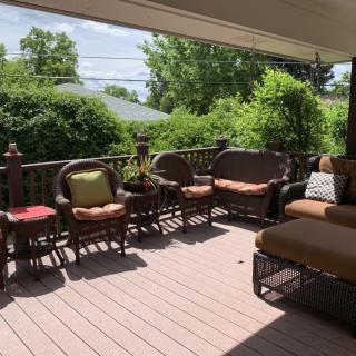 A cozy patio with comfortable outdoor furniture surrounded by lush greenery on a sunny day.
