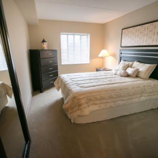A cozy bedroom with a neatly made bed and warm lighting.
