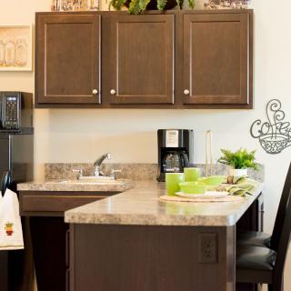 A modern kitchen with dark cabinets, a marble countertop, and various appliances.