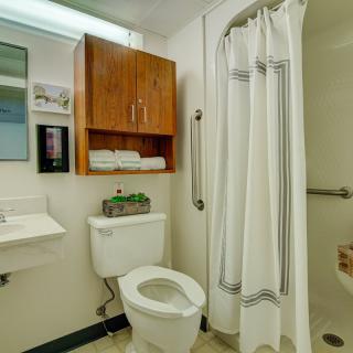 A clean and organized bathroom with a toilet, shower, sink, and storage cabinet.