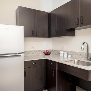 A modern kitchen with dark cabinets and a white refrigerator.