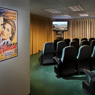 A cozy small theater room with plush seating and a classic movie poster on the wall.