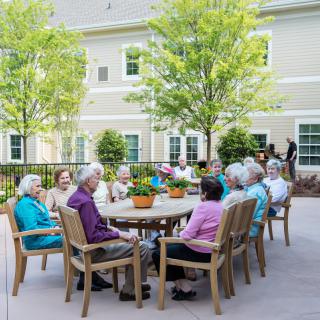 A group of seniors enjoying a gathering outdoors on a sunny day in a retirement community.
