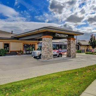 A welcoming hotel entrance with a stone facade under a partly cloudy sky.