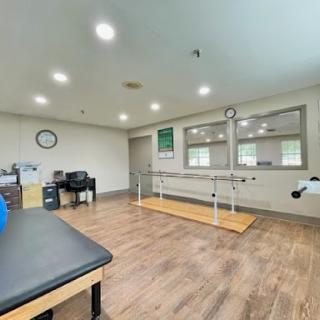 A spacious therapy room equipped with a ballet bar and mirrors, designed for rehabilitation exercises.
