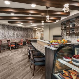 A modern cafe interior featuring a seating area and a well-stocked counter.