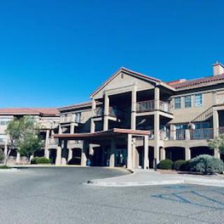 A large residential building complex with a covered entrance under a clear blue sky.