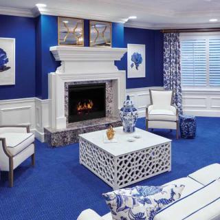 A modern living room with blue and white decor, featuring a fireplace and stylish furniture.