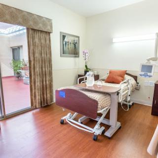 A well-lit hospital room designed for patient comfort, featuring a hospital bed and access to the outdoors.