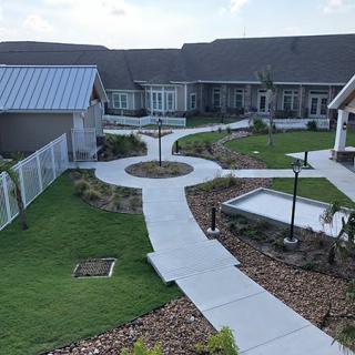 A well-maintained courtyard with multiple pathways and landscaped gardens surrounded by buildings.