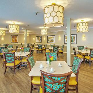 A well-lit dining room with colorful chairs and modern lighting fixtures.