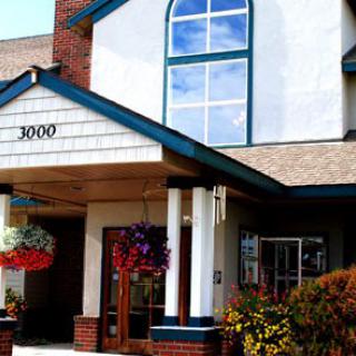 A welcoming entrance to a beautifully designed building, adorned with flowers and large windows.