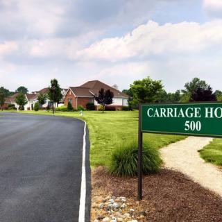A residential neighborhood with a sign reading 'Carriage Ho 500' along a paved road.