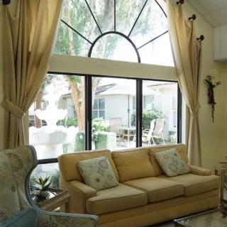 A cozy living room with a large window, elegant curtains, and a comfortable sofa.