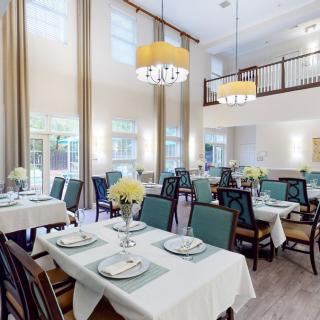 A spacious dining room with neatly arranged tables and elegant chandeliers.