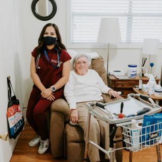 A nurse visits an elderly patient at home, providing care and support.
