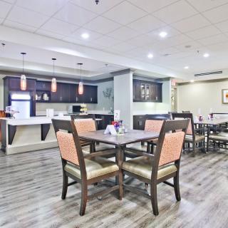 A modern dining area with neatly arranged tables and chairs, and a stylish bar counter in the background.
