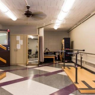 A rehabilitation therapy room equipped with parallel bars and other equipment.