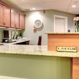 A welcoming reception desk with a 'LAUGH' sign and flowers.
