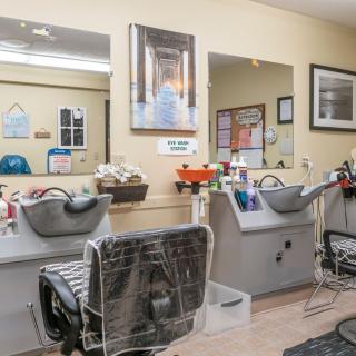 Interior view of a hair salon with styling stations and washing sinks.