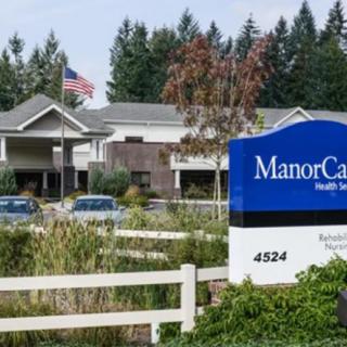 A healthcare facility with a visible sign reading 'ManorCare' surrounded by trees and greenery.