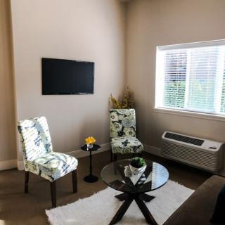 A cozy living room with floral patterned chairs, a mounted TV, and a coffee table.