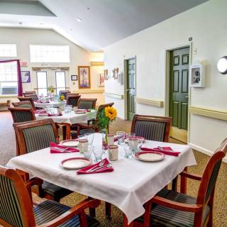 A brightly lit dining area with neatly set tables and comfortable chairs.