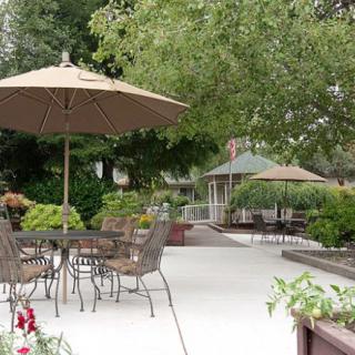 A relaxing outdoor patio area with tables, chairs, and umbrellas surrounded by lush greenery.