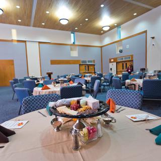 A spacious banquet hall set up with dining tables and chairs, ready for an event.