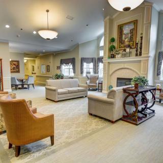 A spacious and elegantly furnished living room with sofas, a fireplace, and decorative chandeliers.
