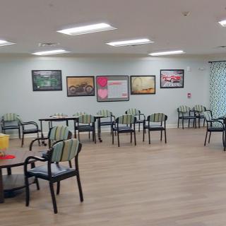 A spacious dining area with neatly arranged chairs and tables, adorned with colorful artwork on the walls.