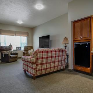 A cozy living room with a plaid sofa, armchairs, and a large television.