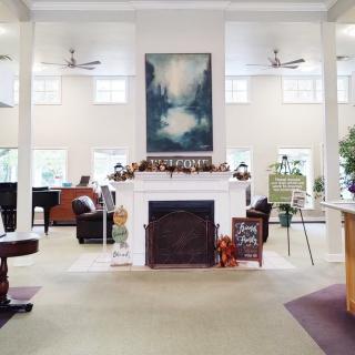 A spacious living room with a central fireplace, artwork above it, and ample seating arrangements.