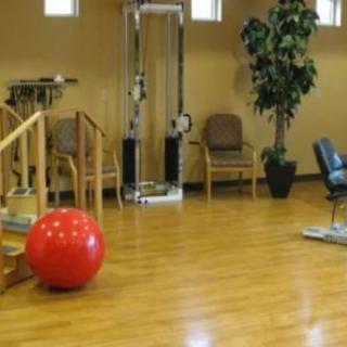 A gym with exercise equipment and a wooden floor.