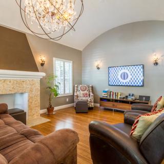 A stylish living room with a modern chandelier, cozy sofas, and a fireplace.