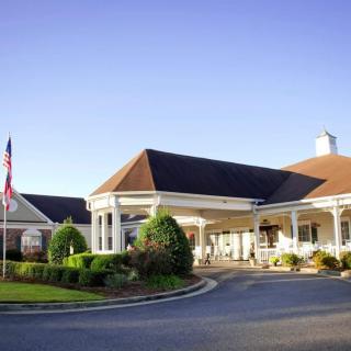 A welcoming entrance to a well-maintained building with an American flag and landscaped surroundings.