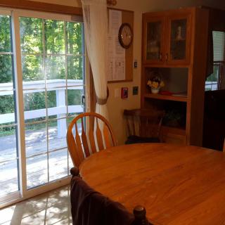 A cozy dining area with a wooden table and chairs, adjacent to a sliding glass door leading to a deck.