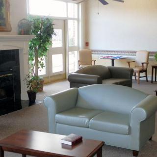 A cozy living room with modern furniture, including sofas and a coffee table, featuring a fireplace and large windows.