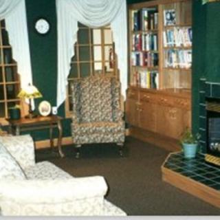 A cozy living room featuring a bookshelf, armchair, sofa, and television.