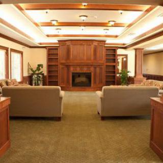 A cozy living room featuring wooden paneling, a central fireplace, and comfortable sofas.