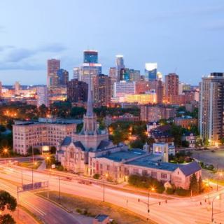 A vibrant city skyline glows in the evening light, showcasing modern architecture and bustling streets.