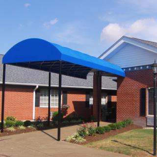 A blue canopy covers the entrance of a building, providing shade and shelter.