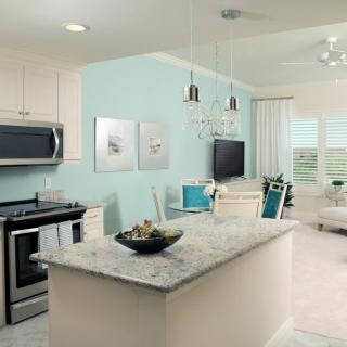 Modern open-concept kitchen and living room with sleek appliances and light decor.