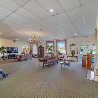 A spacious living room with elegant furnishings, a chandelier, and large windows allowing natural light to fill the space.